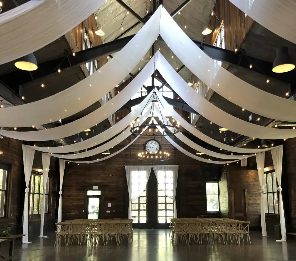 Venue interior with white ceiling draping and chandeliers