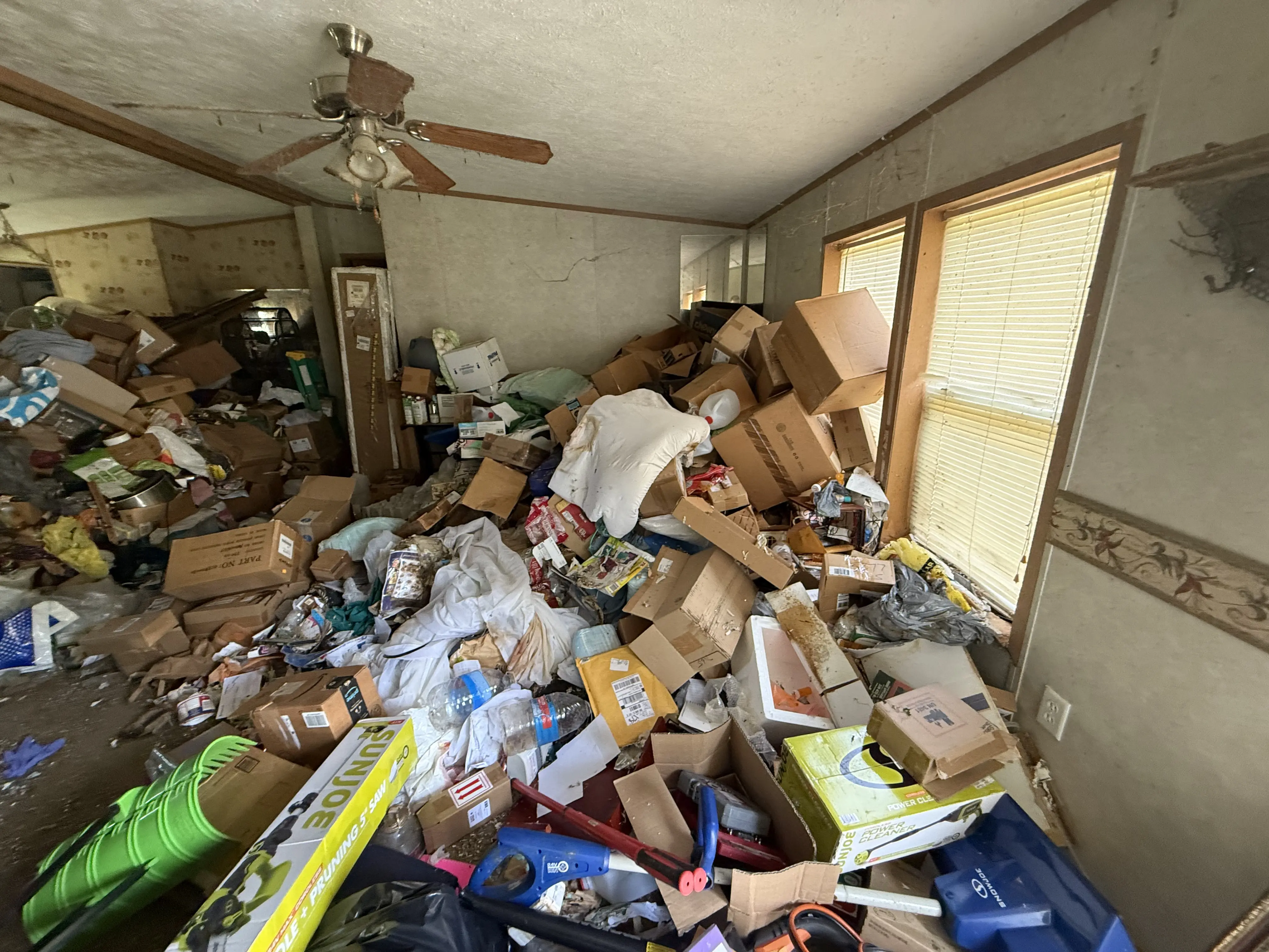 A direct shot of a garage full of clutter , wood , furniture , doors, ect. it looks unorganized.