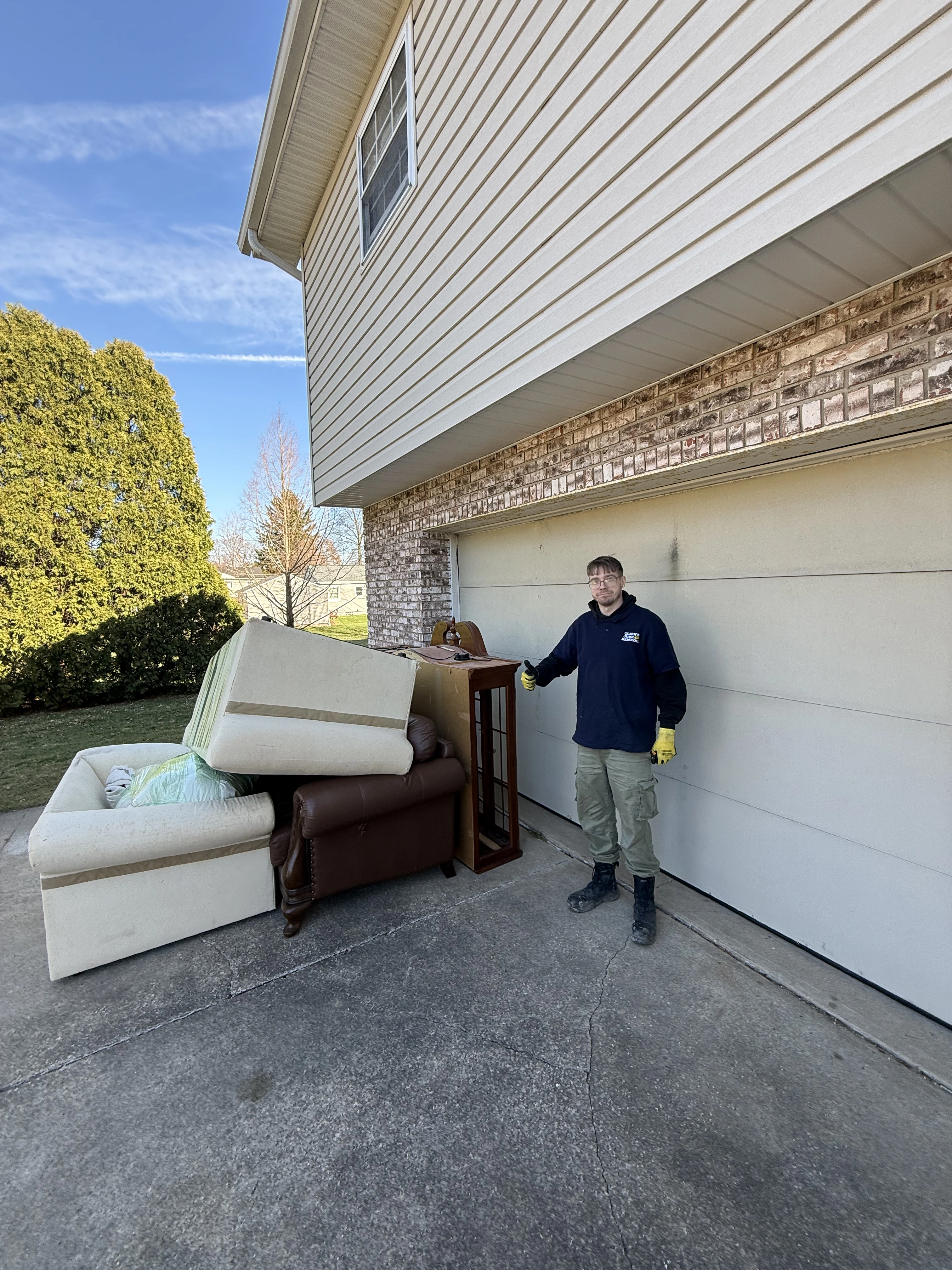 A direct shot of a garage full of clutter , wood , furniture , doors, ect. it looks unorganized.