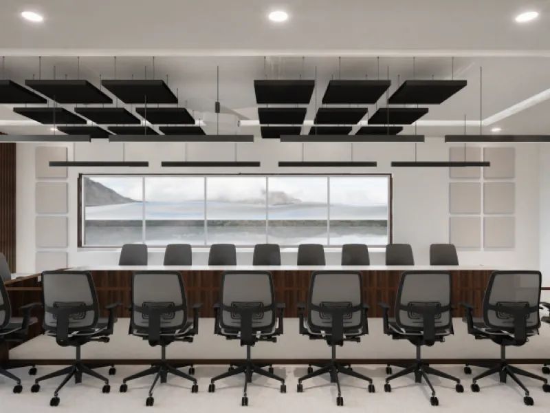 Modern conference room with long table, black office chairs, large window, and ceiling acoustic panels.