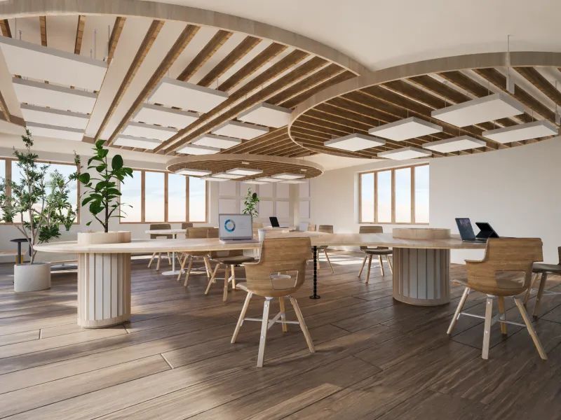 Modern office space with curved wooden desks, chairs, plants, and laptops by large windows.