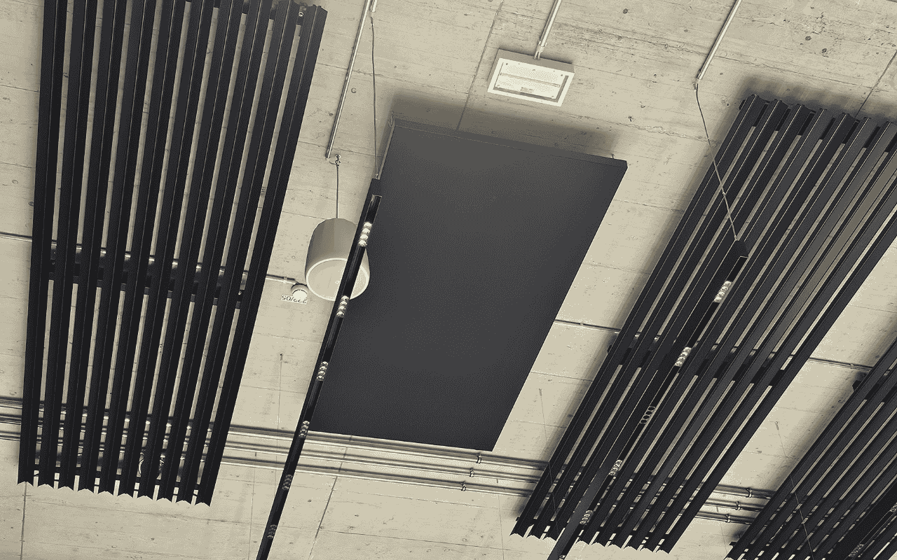 Schwarze Deckenabsorber neben den Deckenheizungen an der Betondecke
