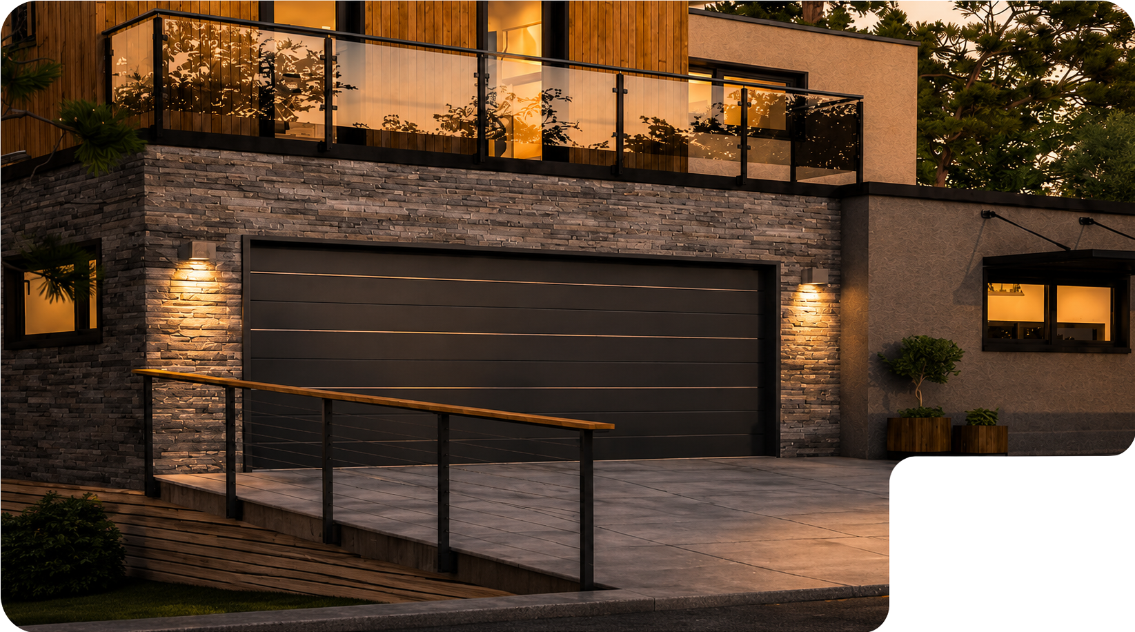 Façade d'une maison moderne avec un garage à porte noire, murs en pierre et bois, balcon vitré à l'étage, éclairage extérieur chaud et plantes décoratives près d'une large allée en béton.
