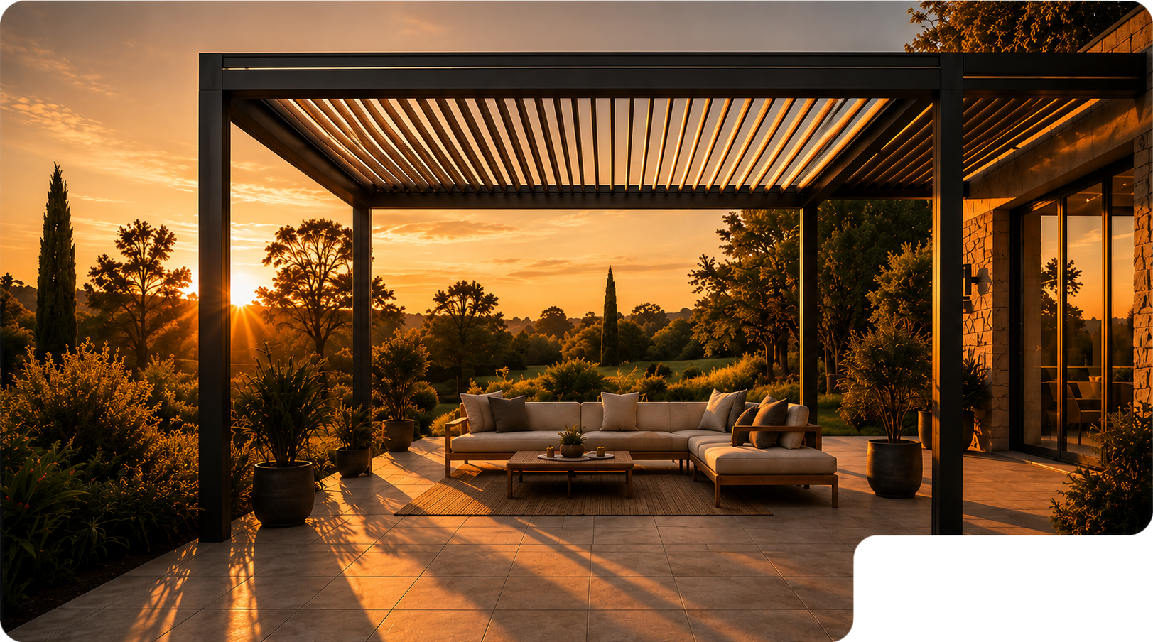 Terrasse moderne avec canapé d'angle beige sous une pergola noire au coucher du soleil, entourée de plantes en pots avec vue sur un jardin et arbres en arrière-plan.