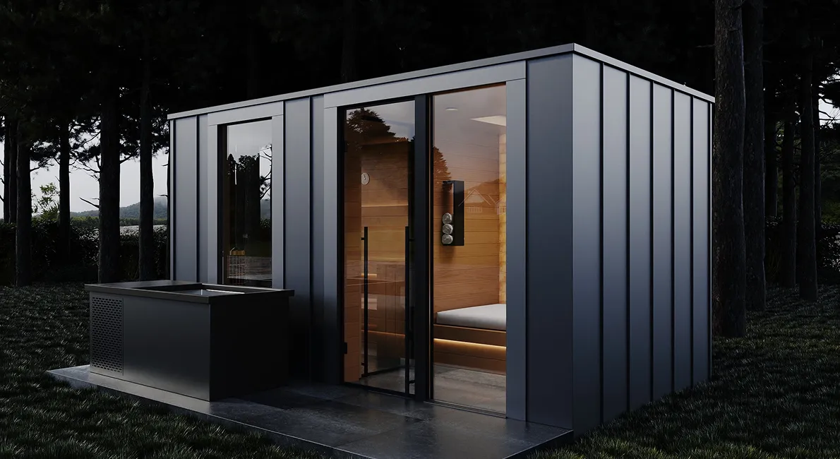 Nowoczesna sauna na zewnątrz z czarną obudową i dużym oknem, na podłożu z żwiru obok innych mebli ogrodowych.