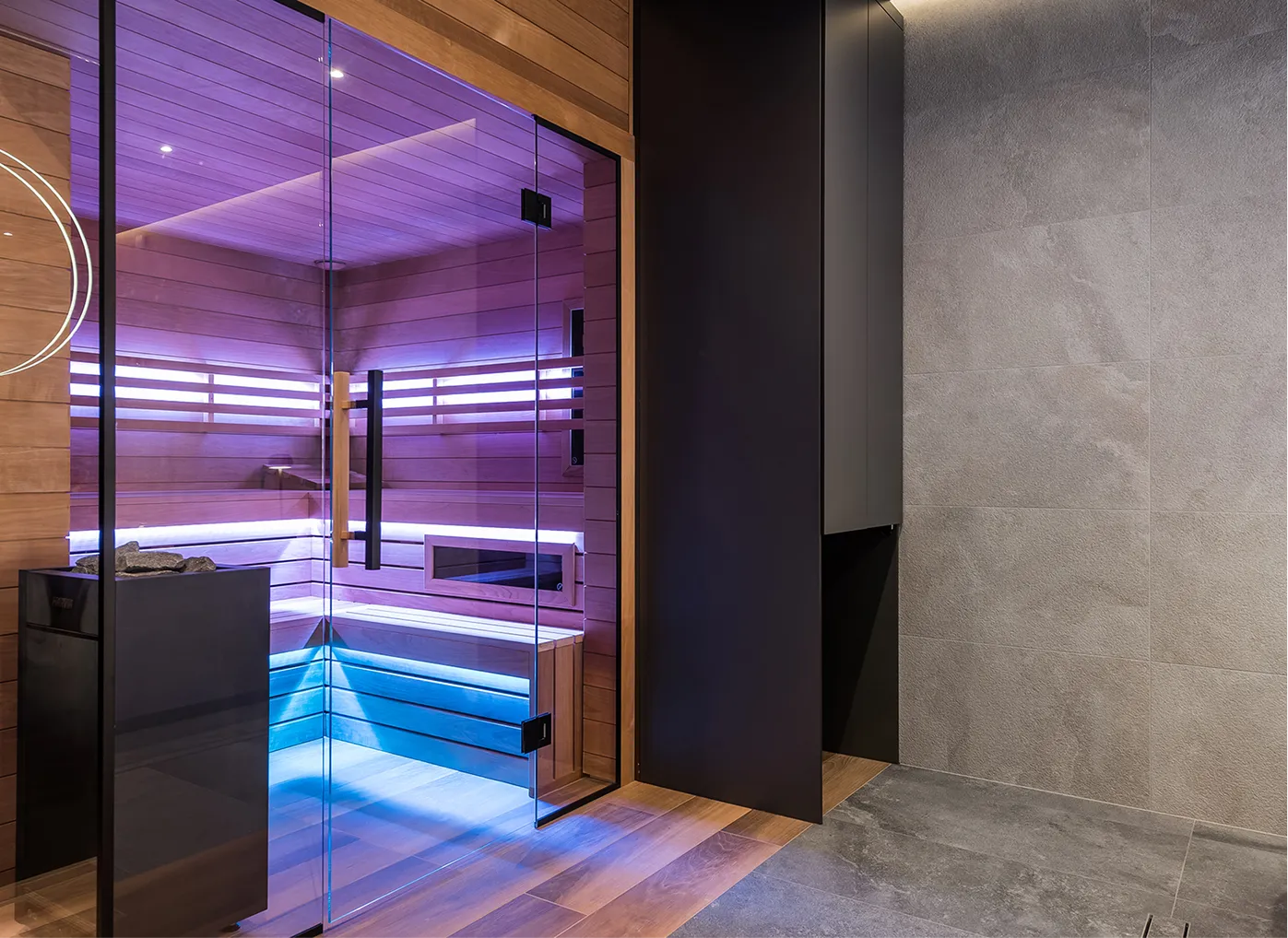 Nowoczesna sauna z przezroczystymi drzwiami szklanymi i podświetlanymi ławkami w drewnianym wnętrzu.