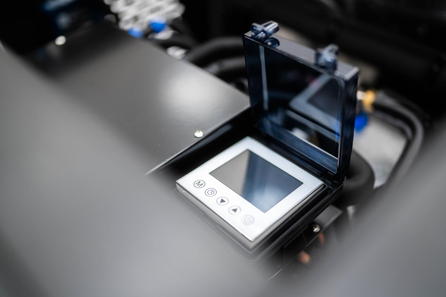 Elektroniczny wyświetlacz z otwartą plastikową osłoną, zamontowany na czarnym urządzeniu.