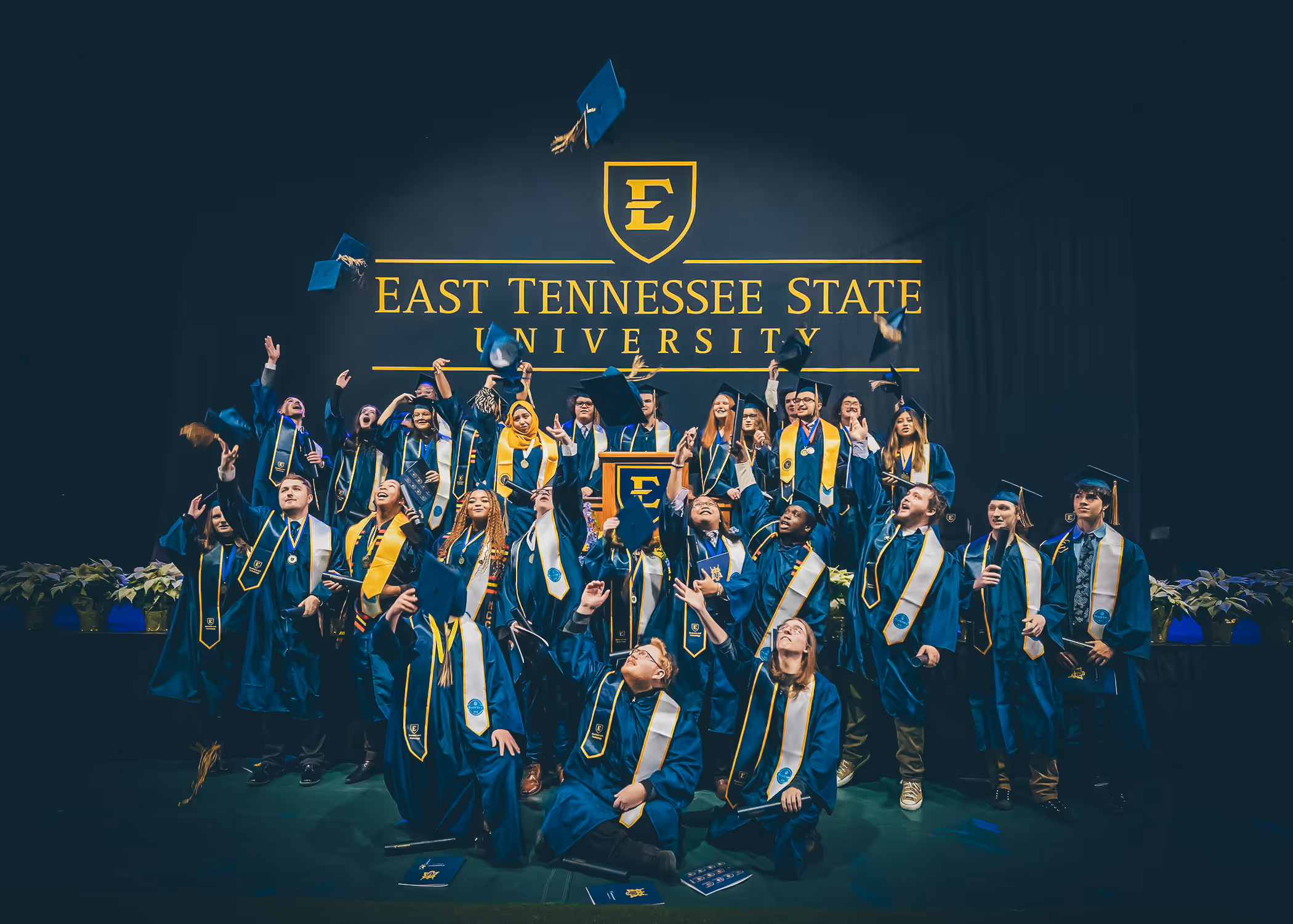 Graduates from the inaugural class of the BlueSky Tennessee Institute throwing their caps in the air at graduation