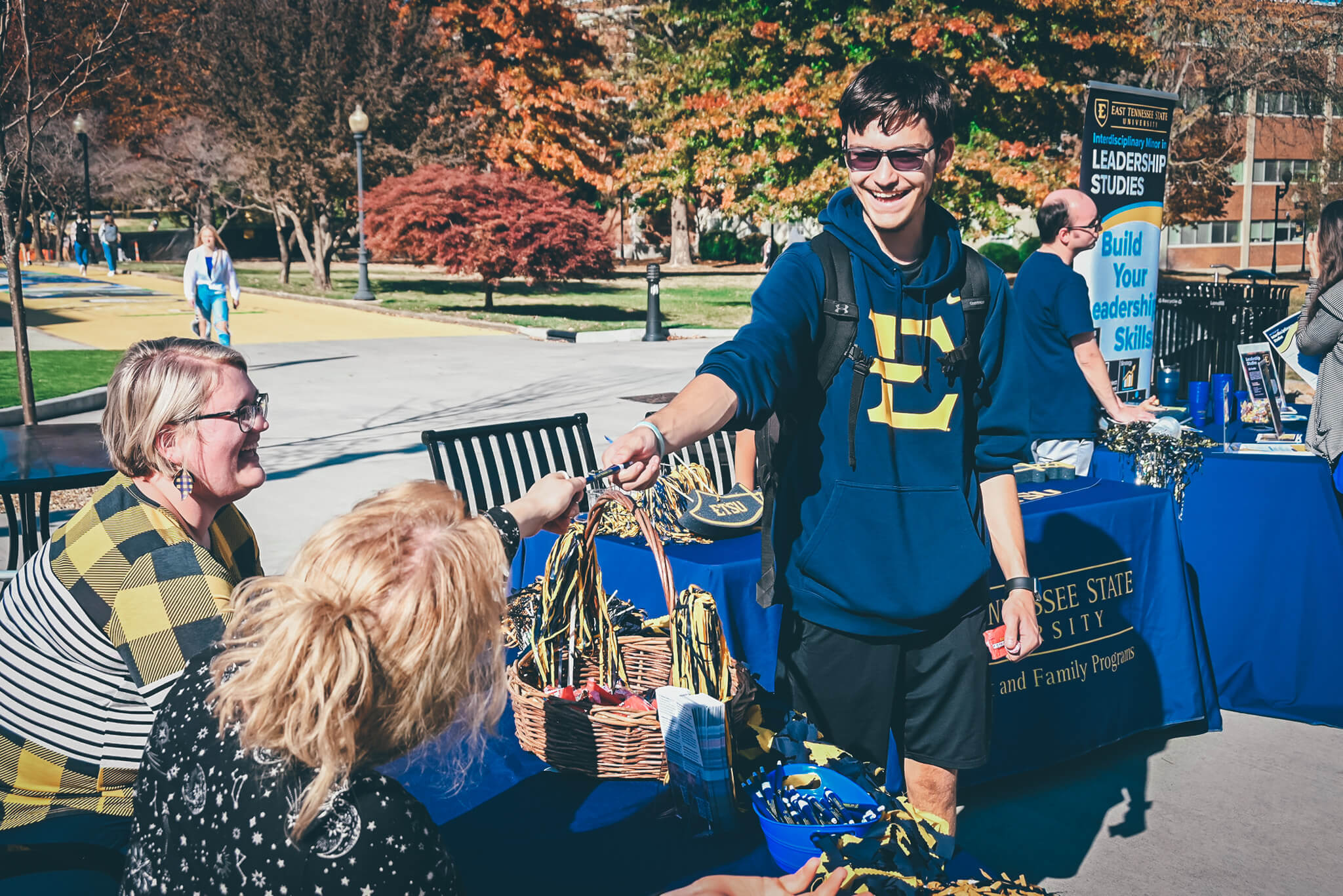 Student standing at a table talking to two staff members