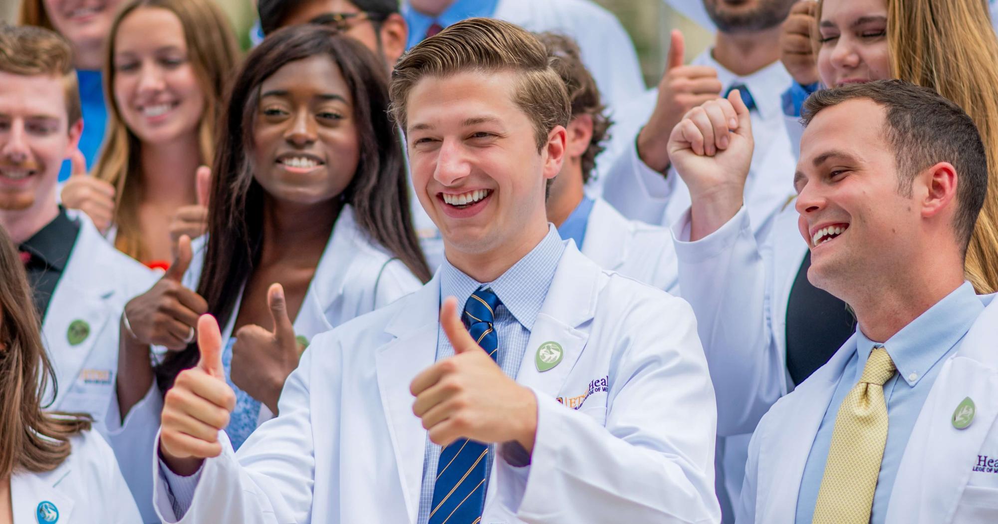 A student smiles and gives a thumbs up.