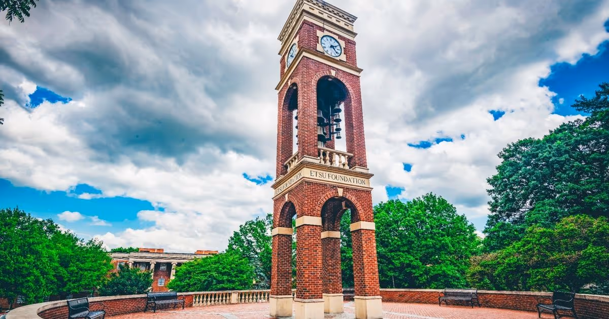 The ETSU bell tower stands with blue skies and white clouds in the background.