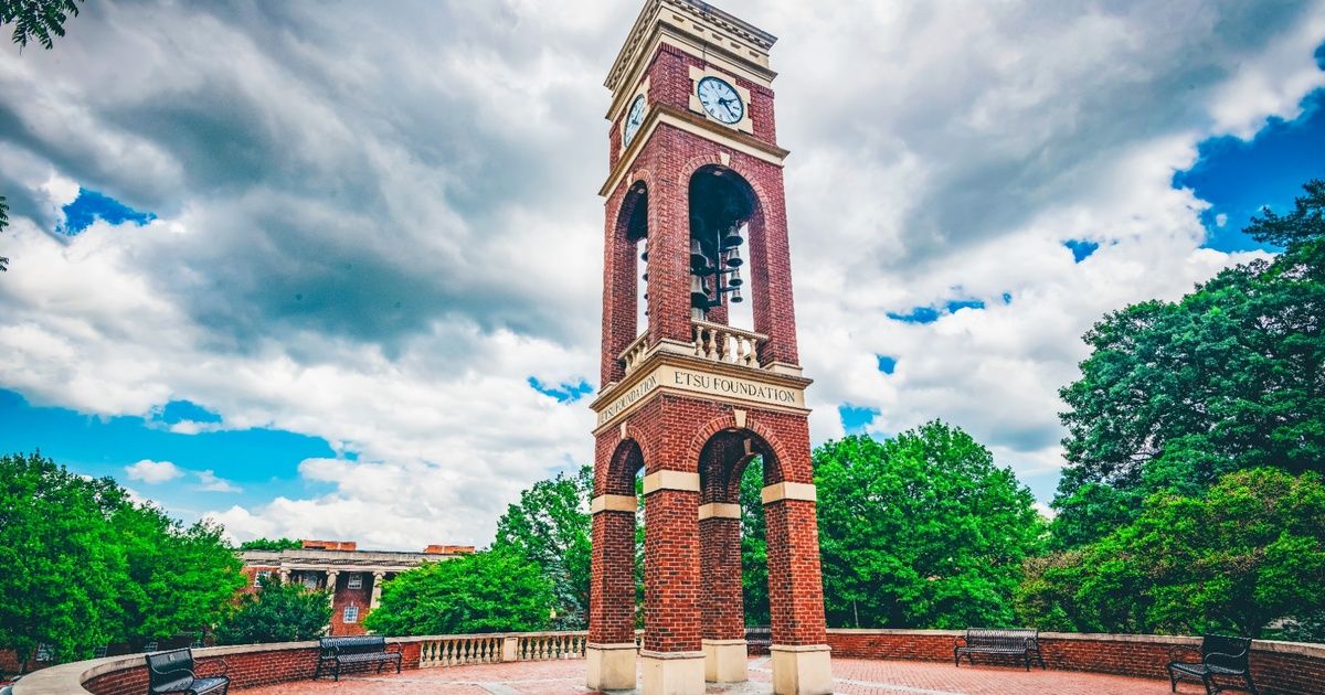 The ETSU bell tower stands with blue skies and white clouds in the background.