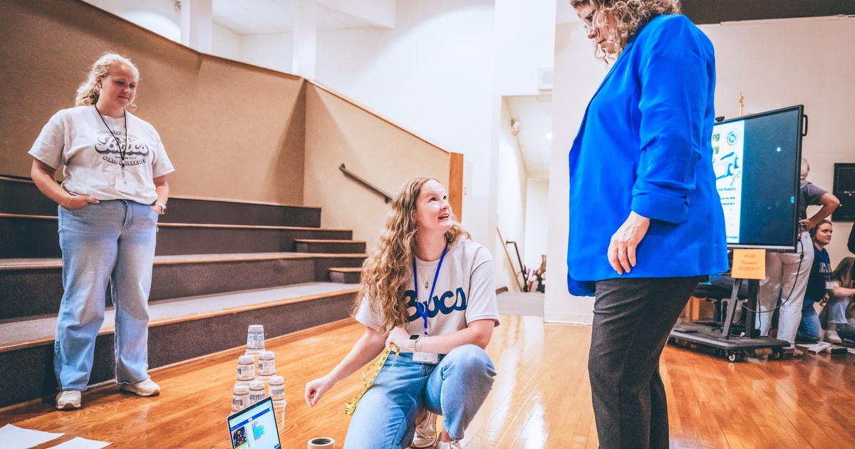 ETSU student shares a laptop screen displaying a coding and mapping project while explaining her STEM work to a faculty member.