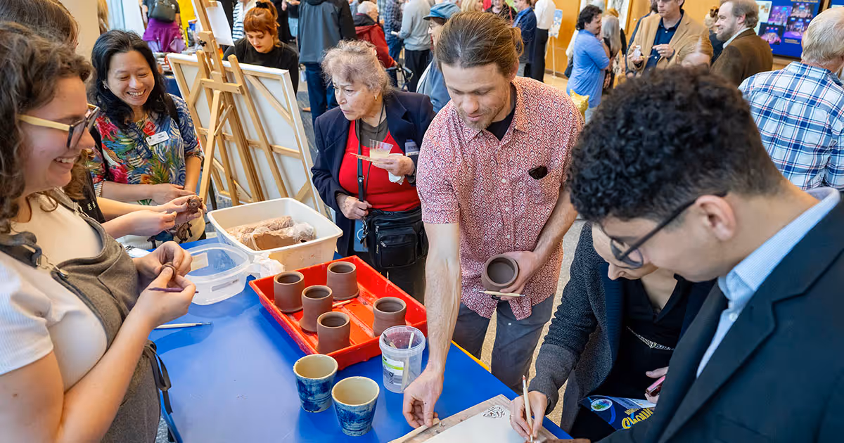 Guests interact with students during a hands-on ceramics demonstration as part of the Mary B. Martin School of the Arts Showcase.