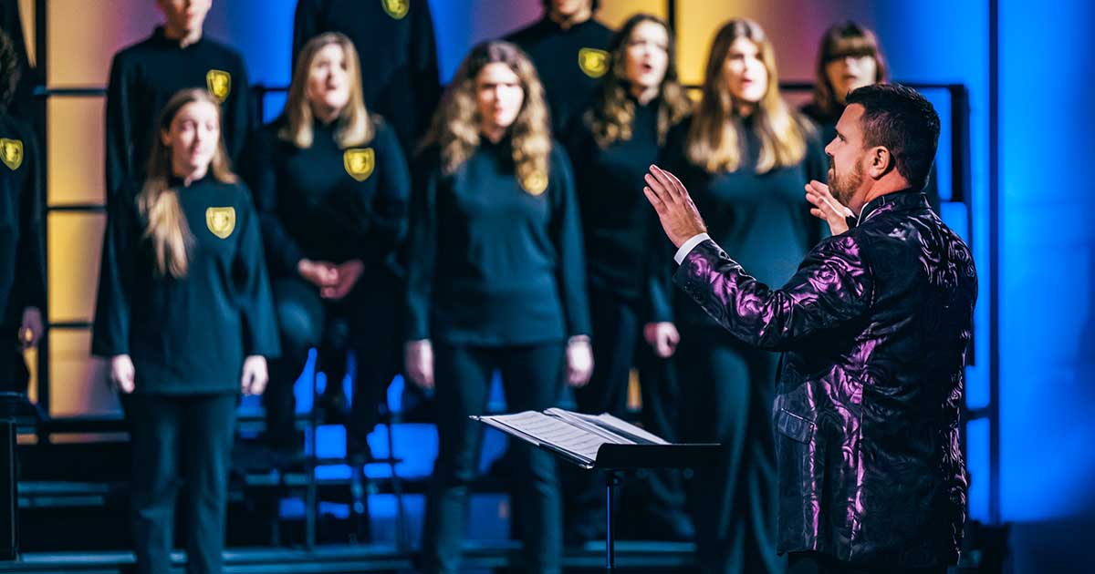 In a purple blazer, Dr. Alan Stevens directs ETSU Chorale.