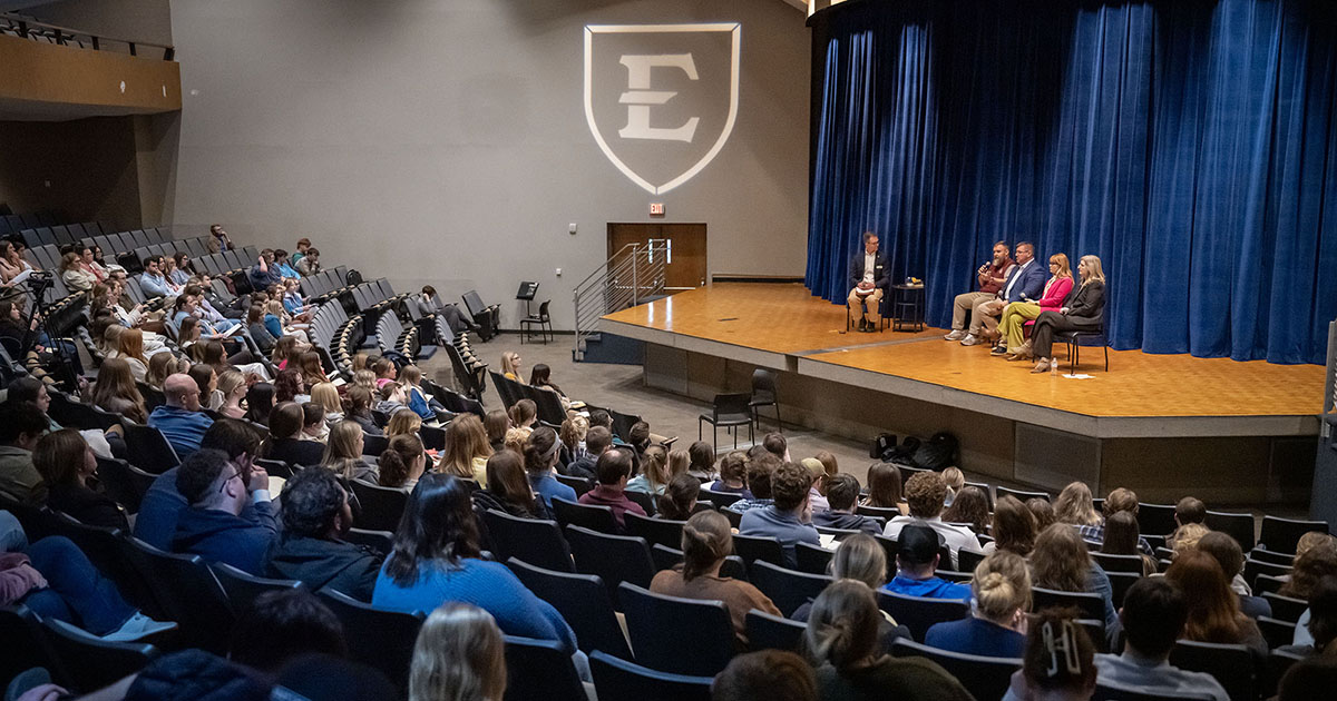 A panel discusses educational topics at ETSU with dozens of students in the audience.