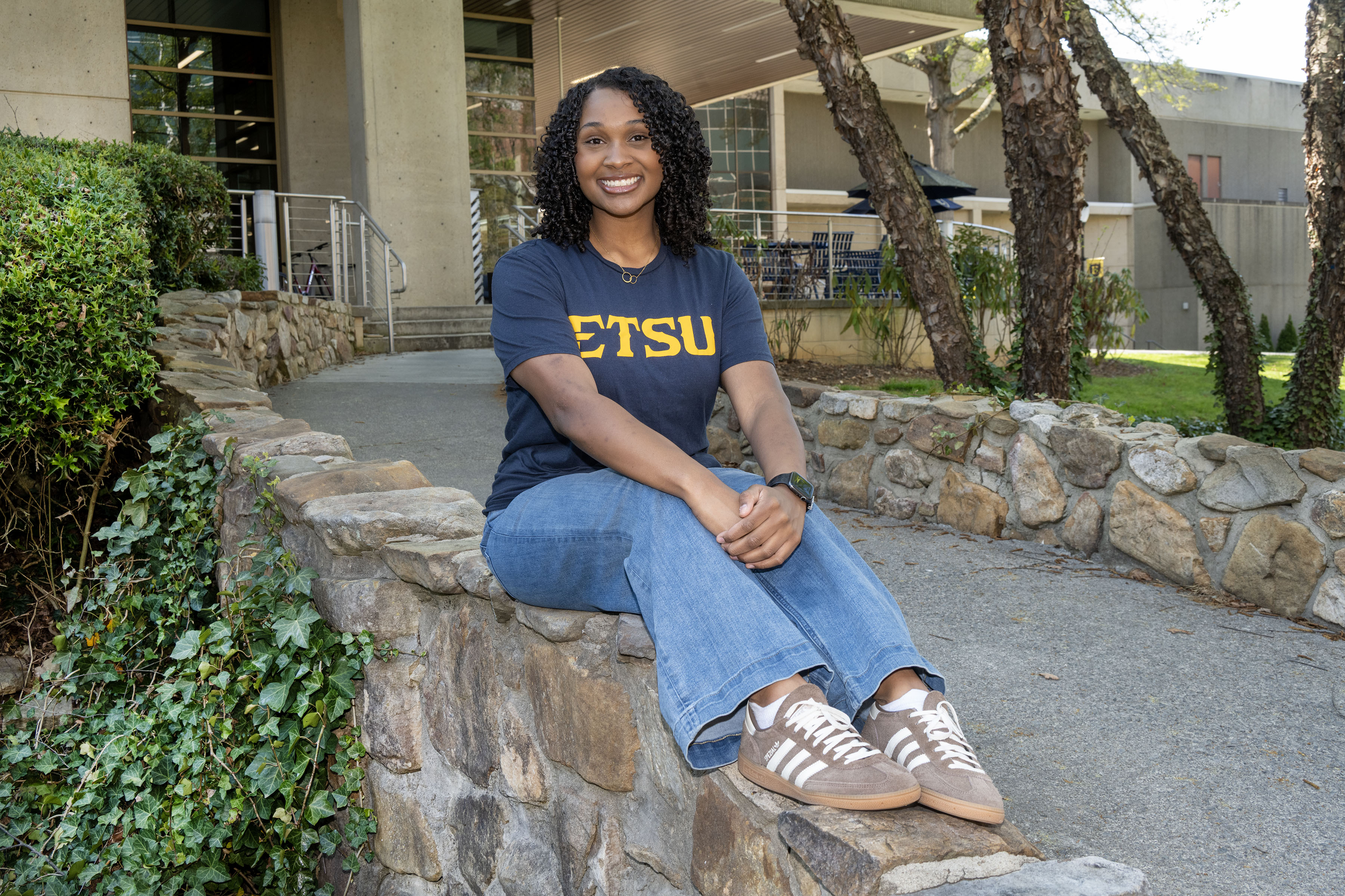 Nancy sits on the bridge outside of the D.P. Culp Student Center, with her legs and arms out in front of her.