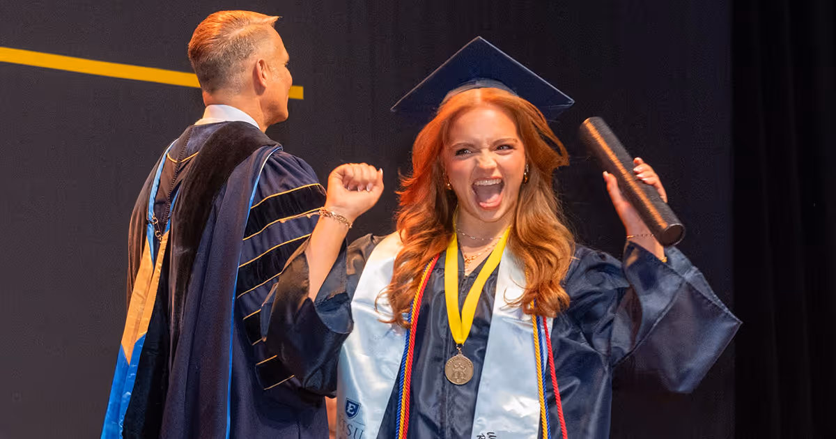 A student cheers as she crosses the stage to collect her diploma