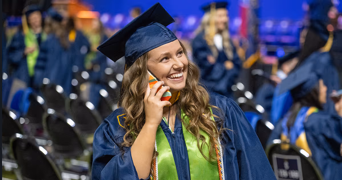 A graduate smiles while talking on the phone