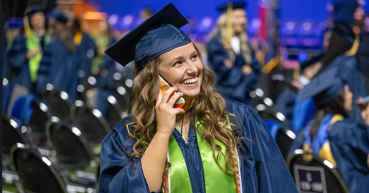 A graduate smiles while talking on the phone