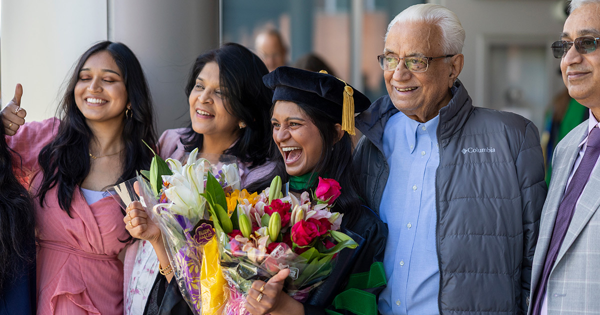 A graduate receives flowers from her smiling family