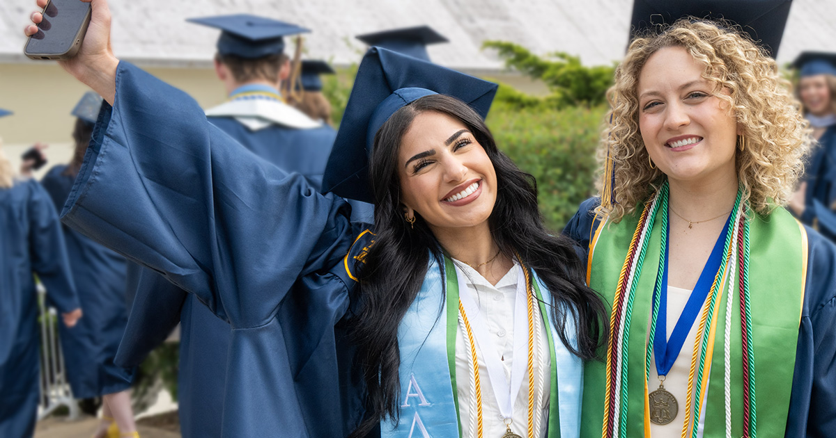 Two graduates hug and smile