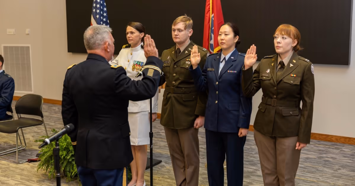 The Quillen College of Medicine's military students stand in a line and hold up a hand while being sworn into the military on Friday, May 8.