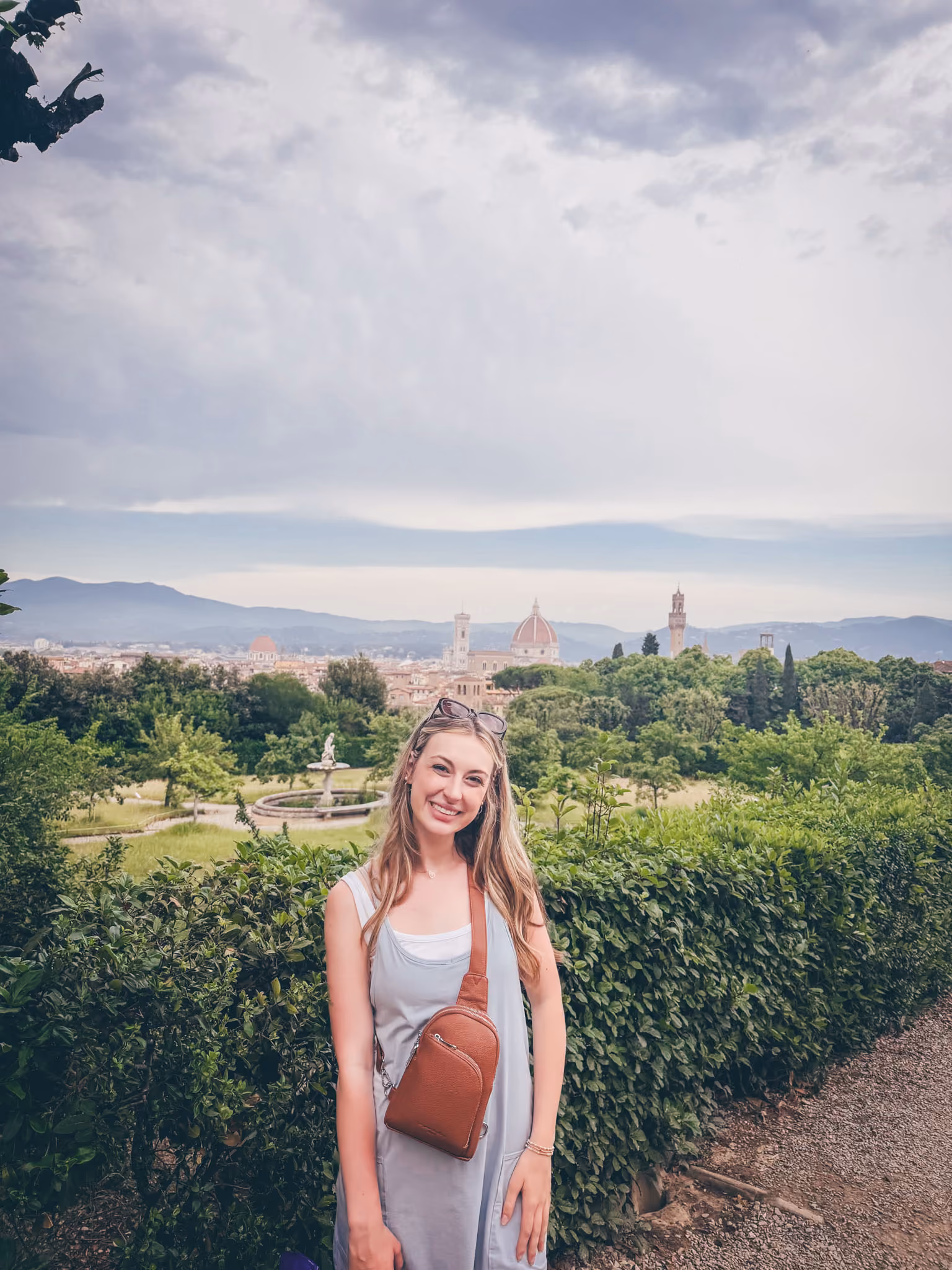 ETSU student Emma Hurley stands in front of a shrub hedge under a cloudy sky in Italy.