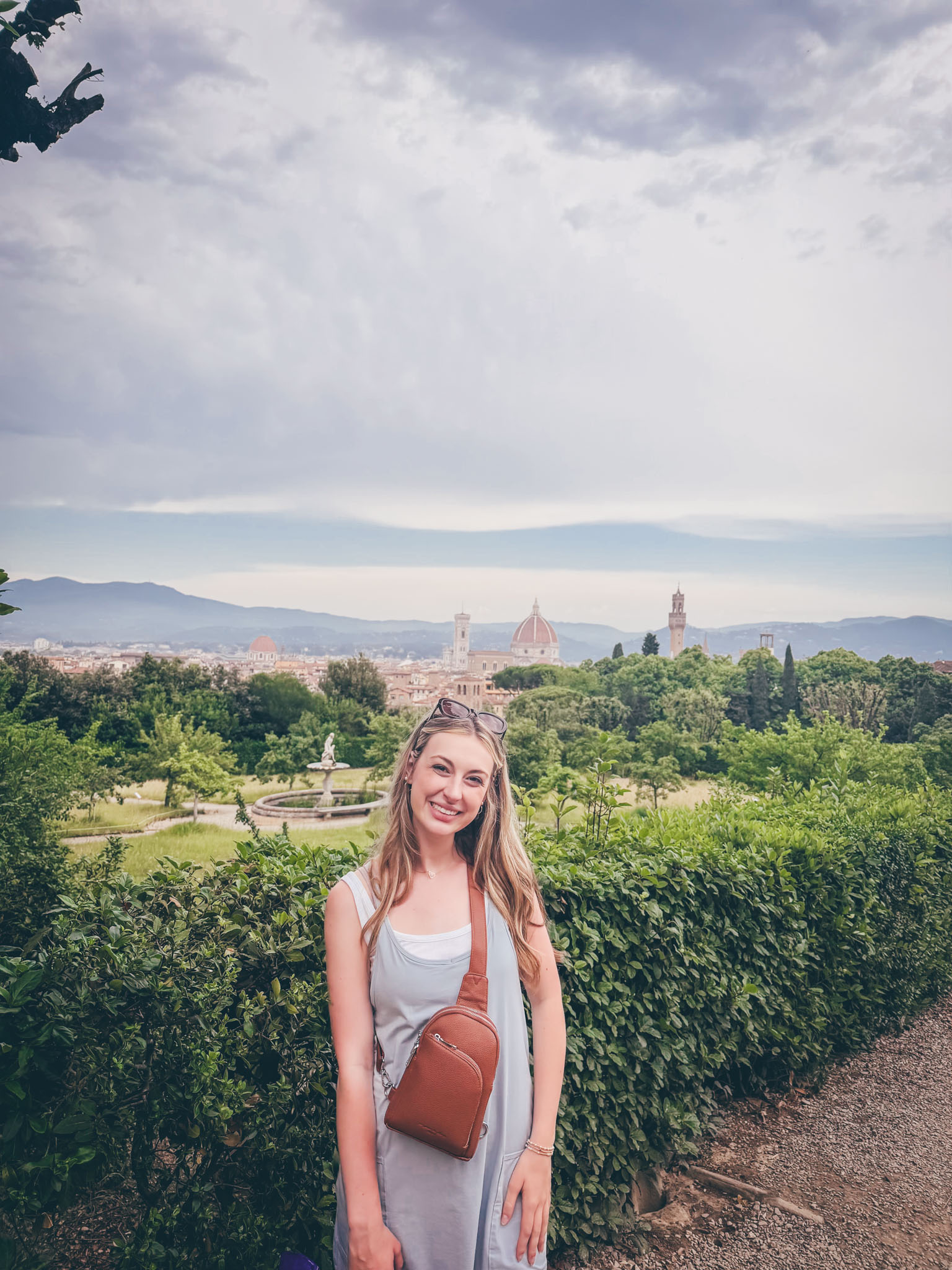 ETSU student Emma Hurley stands in front of a shrub hedge under a cloudy sky in Italy.