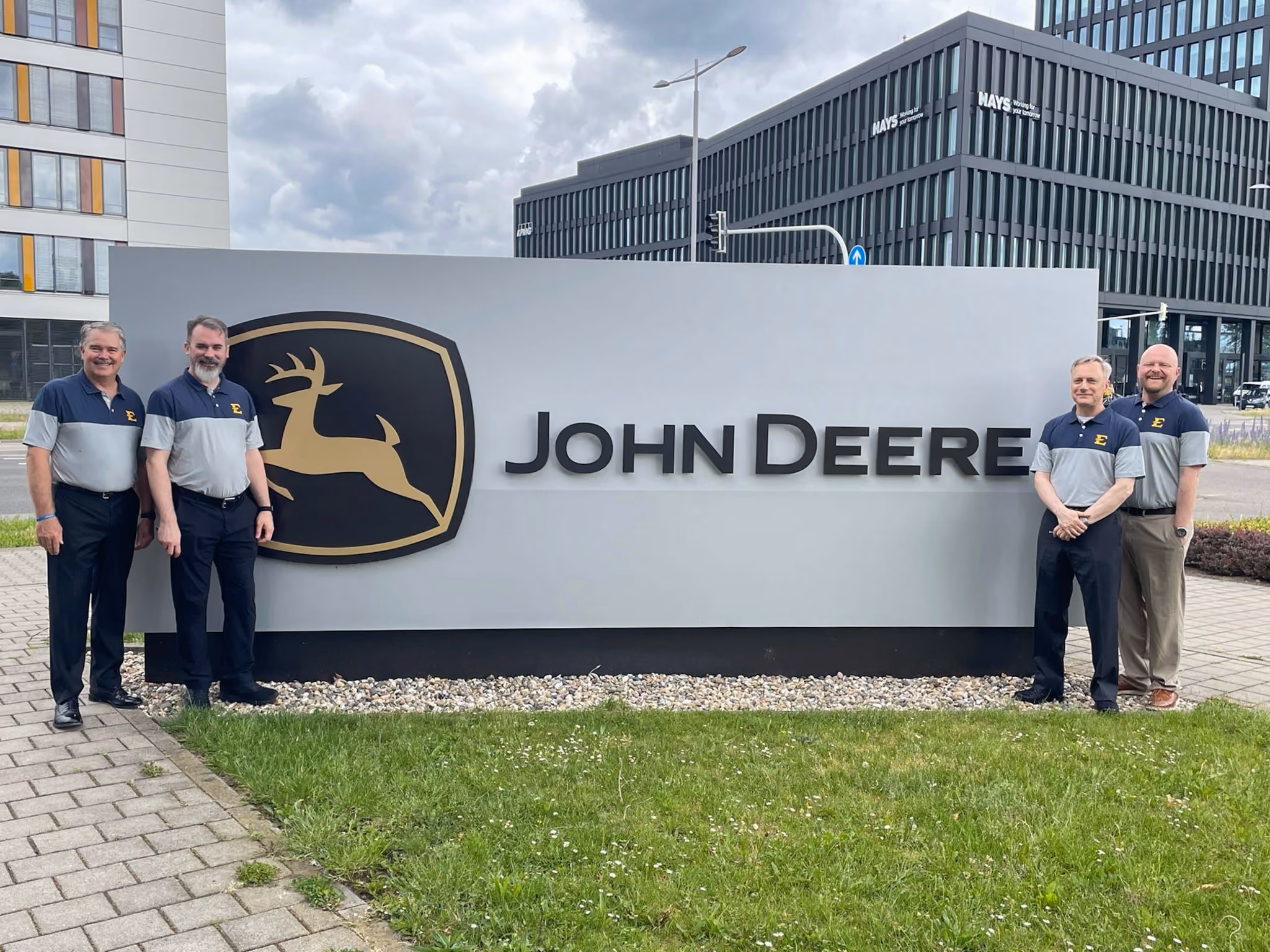 The four ETSU computing faculty smile and pose with the John Deere sign in Germany.