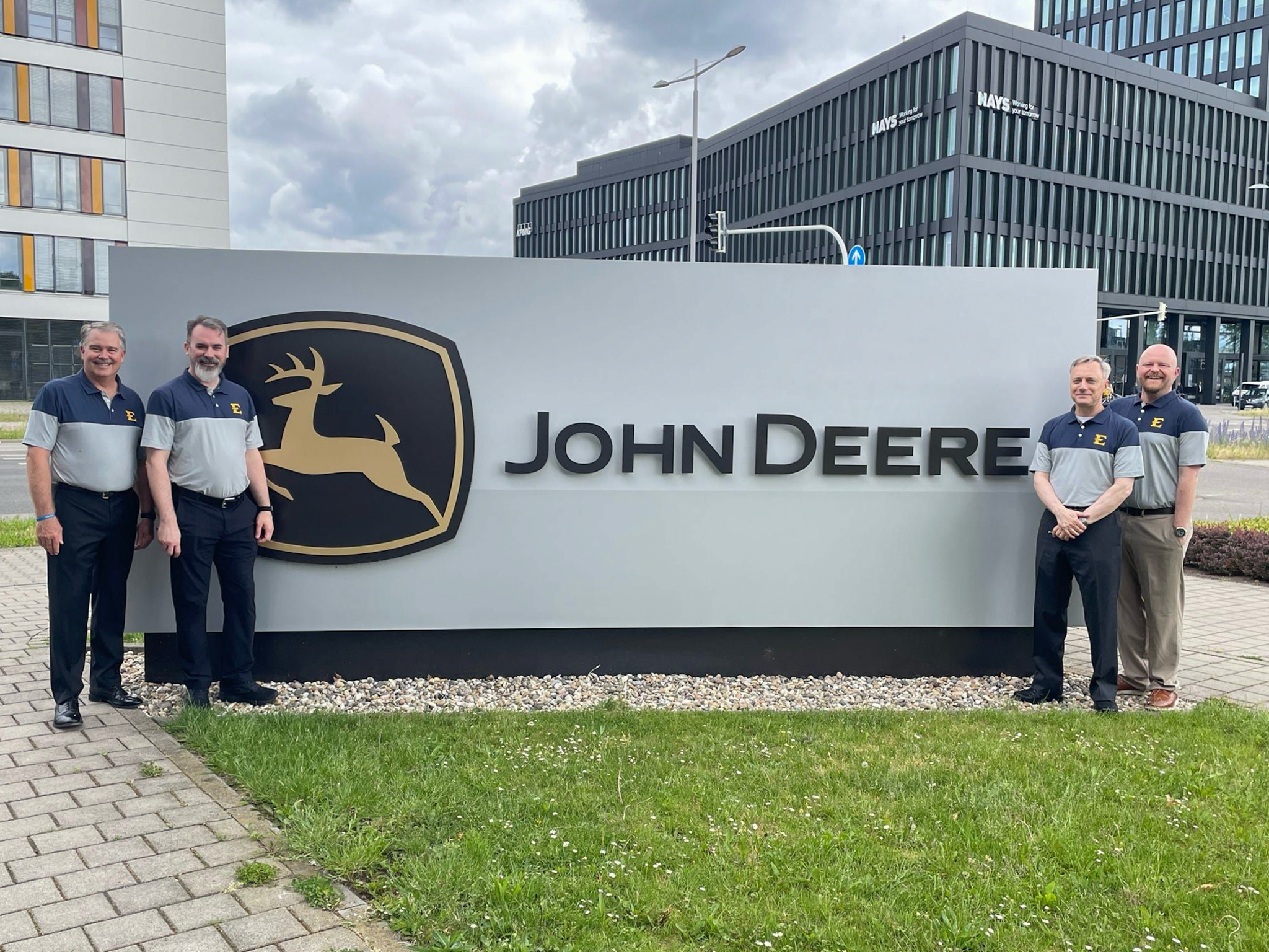 The four ETSU computing faculty smile and pose with the John Deere sign in Germany.