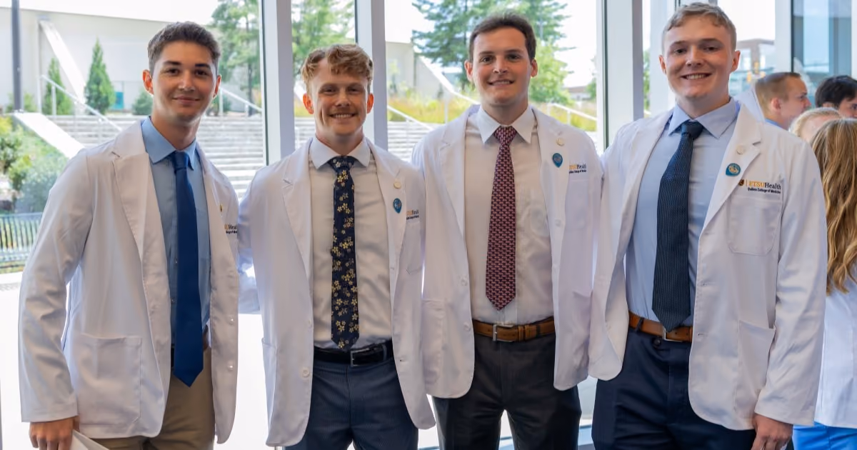 Four Quillen College of Medicine students pose for a photo together after receiving their white coats.