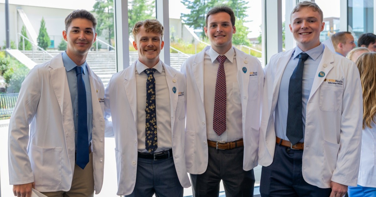 Four Quillen College of Medicine students pose for a photo together after receiving their white coats.