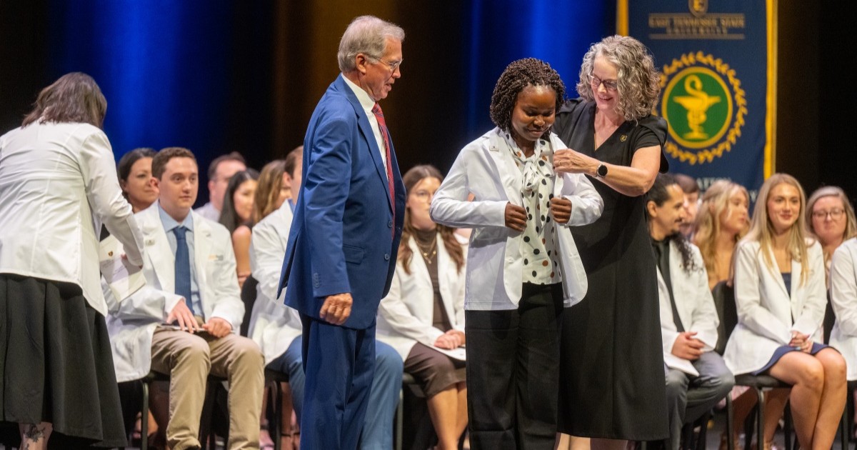 Dean Debbie Byrd helps a student put on their white coat during the White Coat Ceremony on Friday.