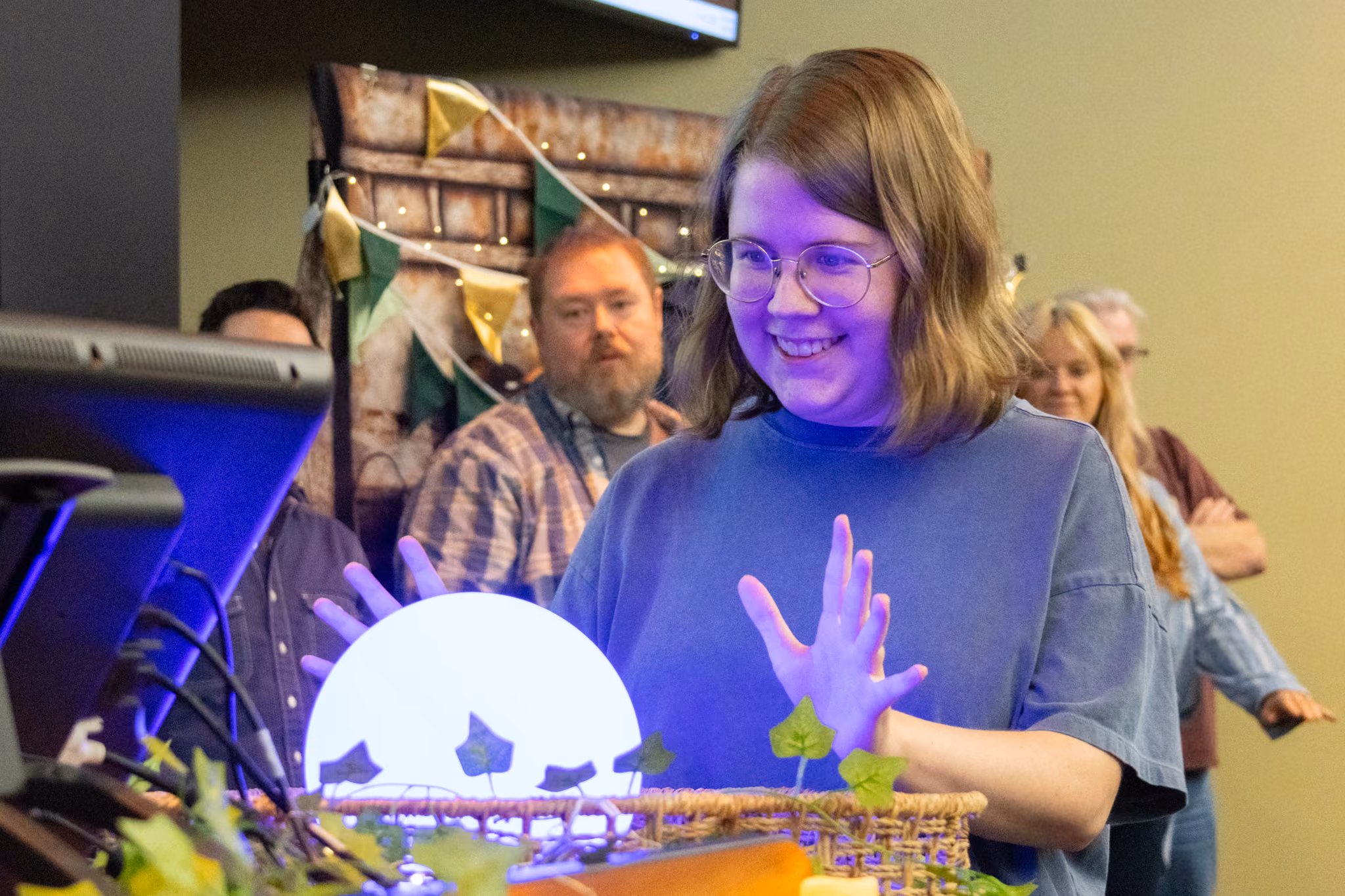 An ETSU CBAT digital media student smiles as they ponder the blue/purple orb.