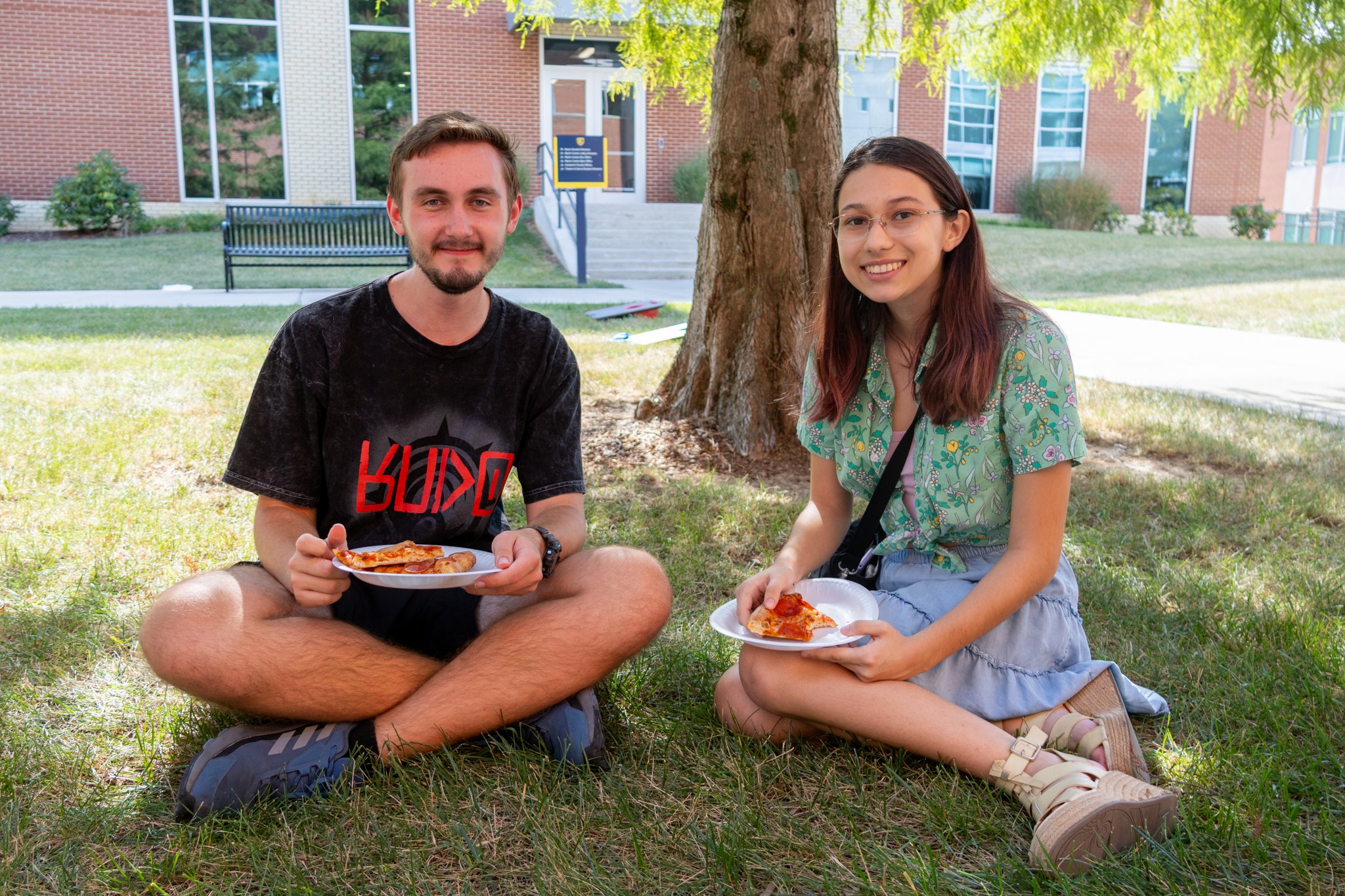 Two ETSU computing students smile while sitting under a tree at the computing Welcome Back Bash.