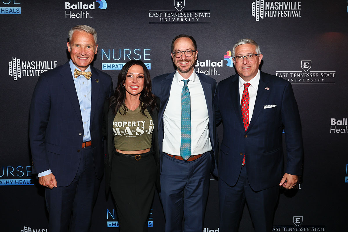 A group photo with four people smiling.