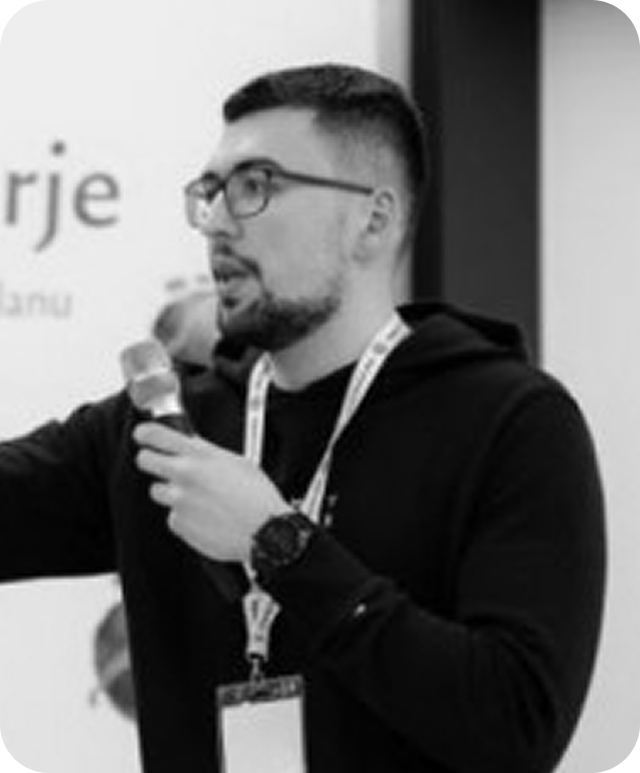 Black and white picture of Matej speaking on stage