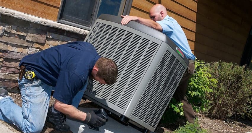 Two technicians installing new HVAC unit