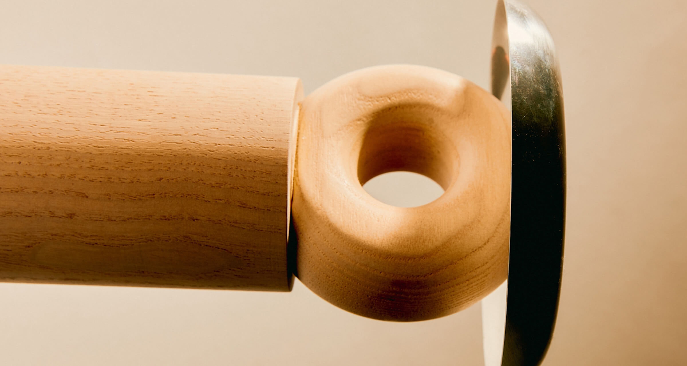 Wooden cylinder and ring joined to a mirrored disc on a beige background
