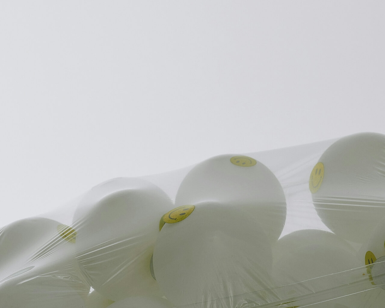 White balls with yellow smiley faces wrapped in clear plastic film