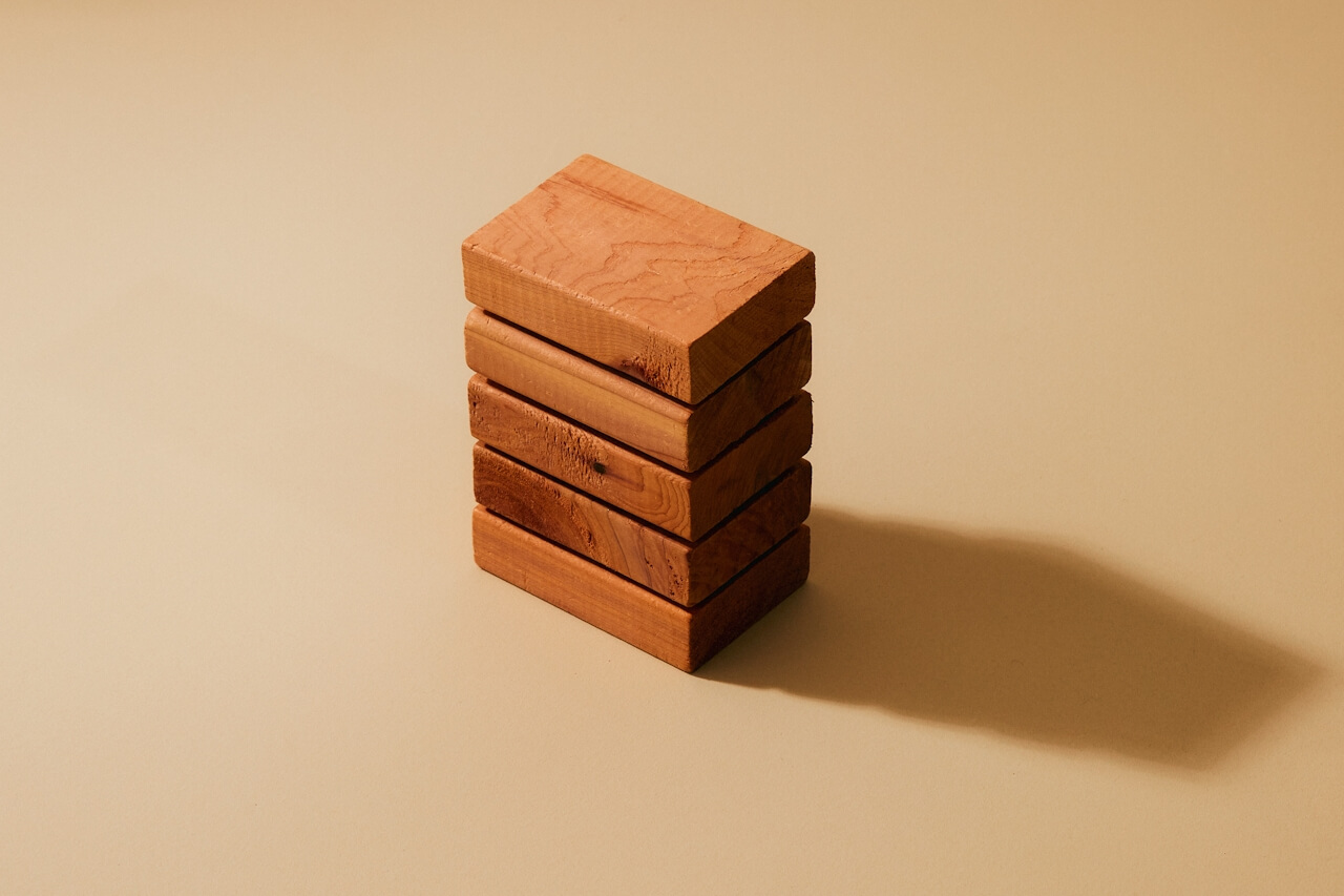 Stack of five wooden blocks casting a long shadow on a beige surface