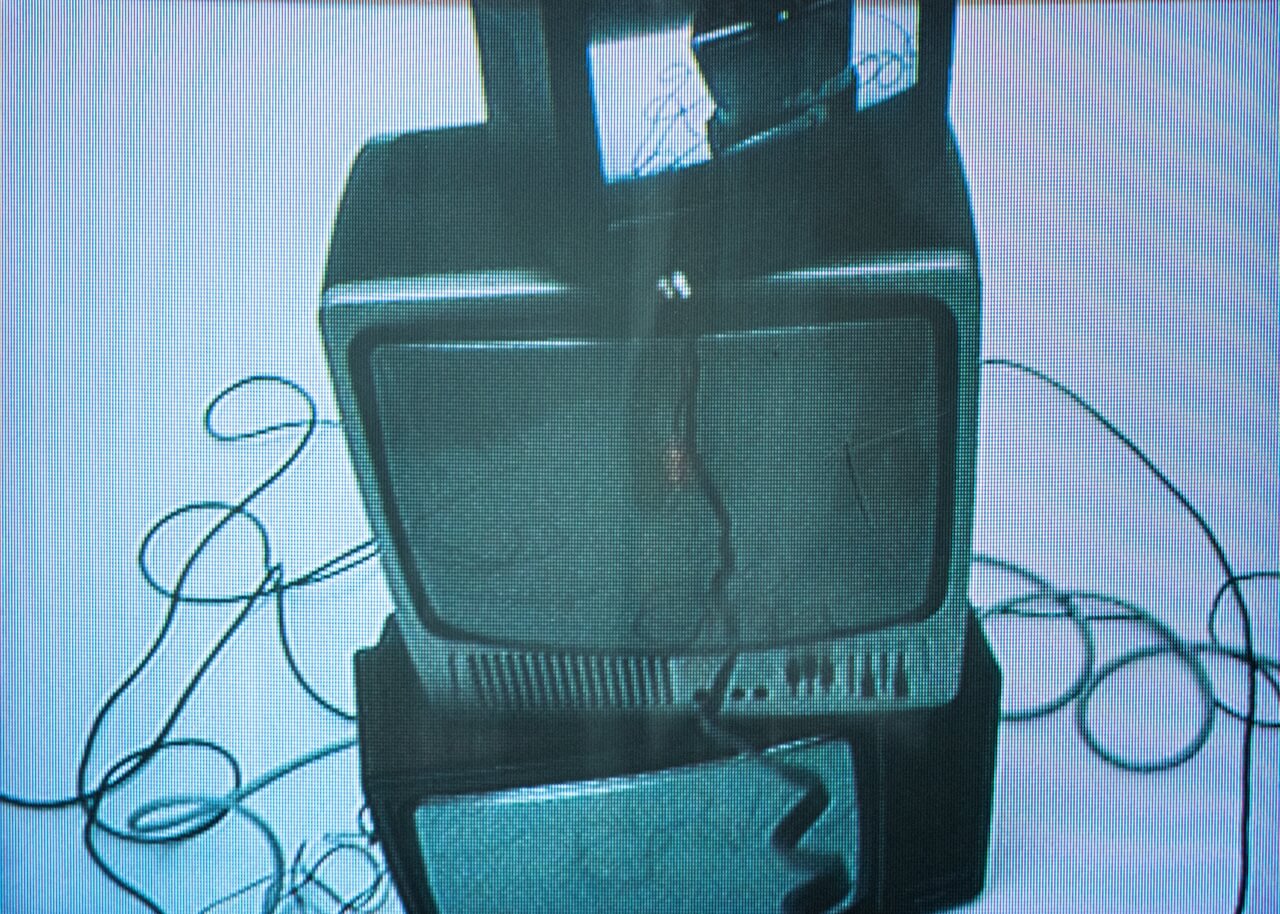 Stacked vintage TV sets with tangled cables in blue-tinted light