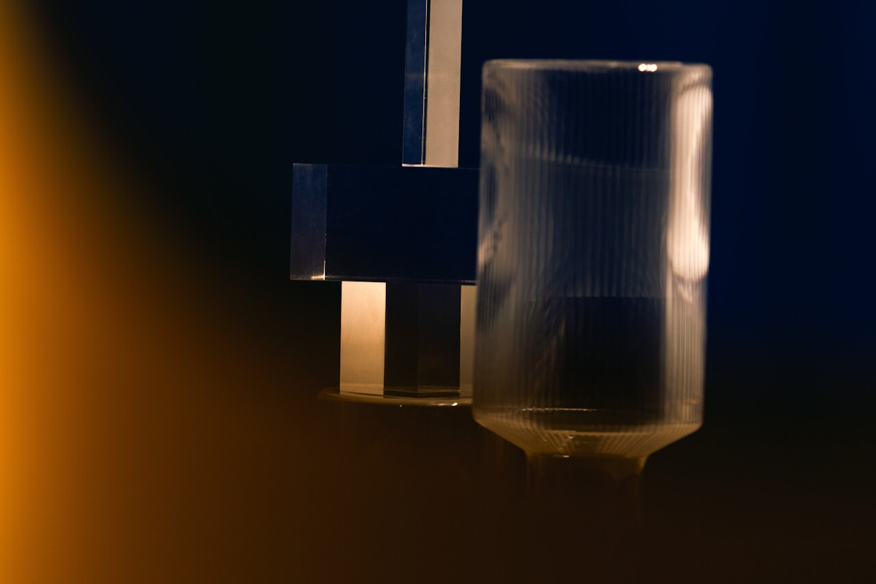 Glass and metal objects lit by warm orange light against a dark blue background
