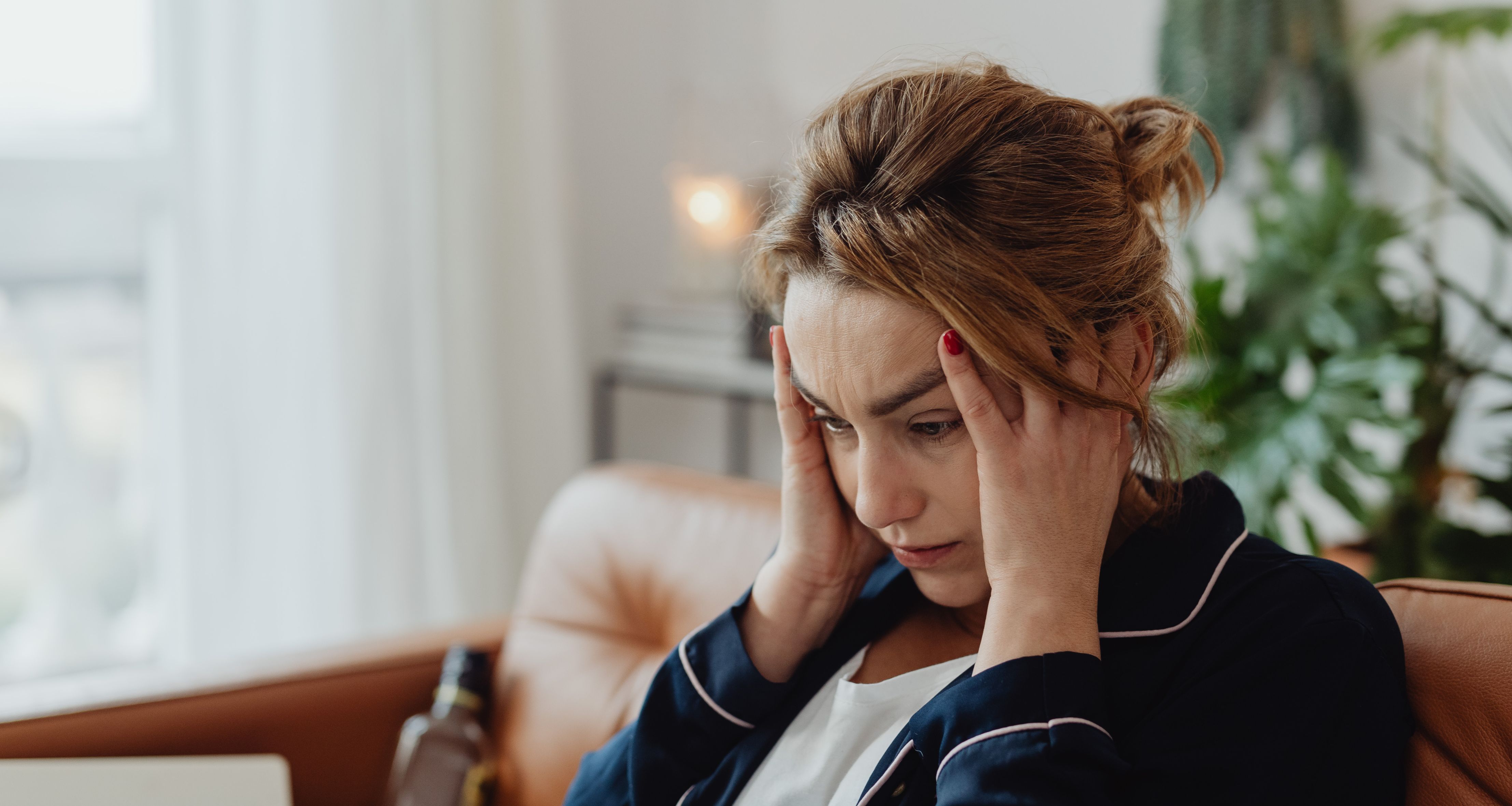 Frau legt die Hände an die Schläfe und schaut ins leere