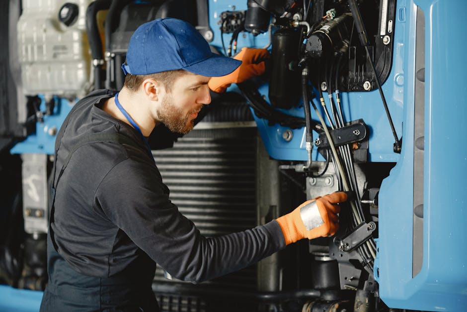 Skilled worker in safety gear repairing industrial equipment.