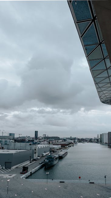 A contemporary harbor scene featuring ships under an overcast sky, showcasing urban architecture.