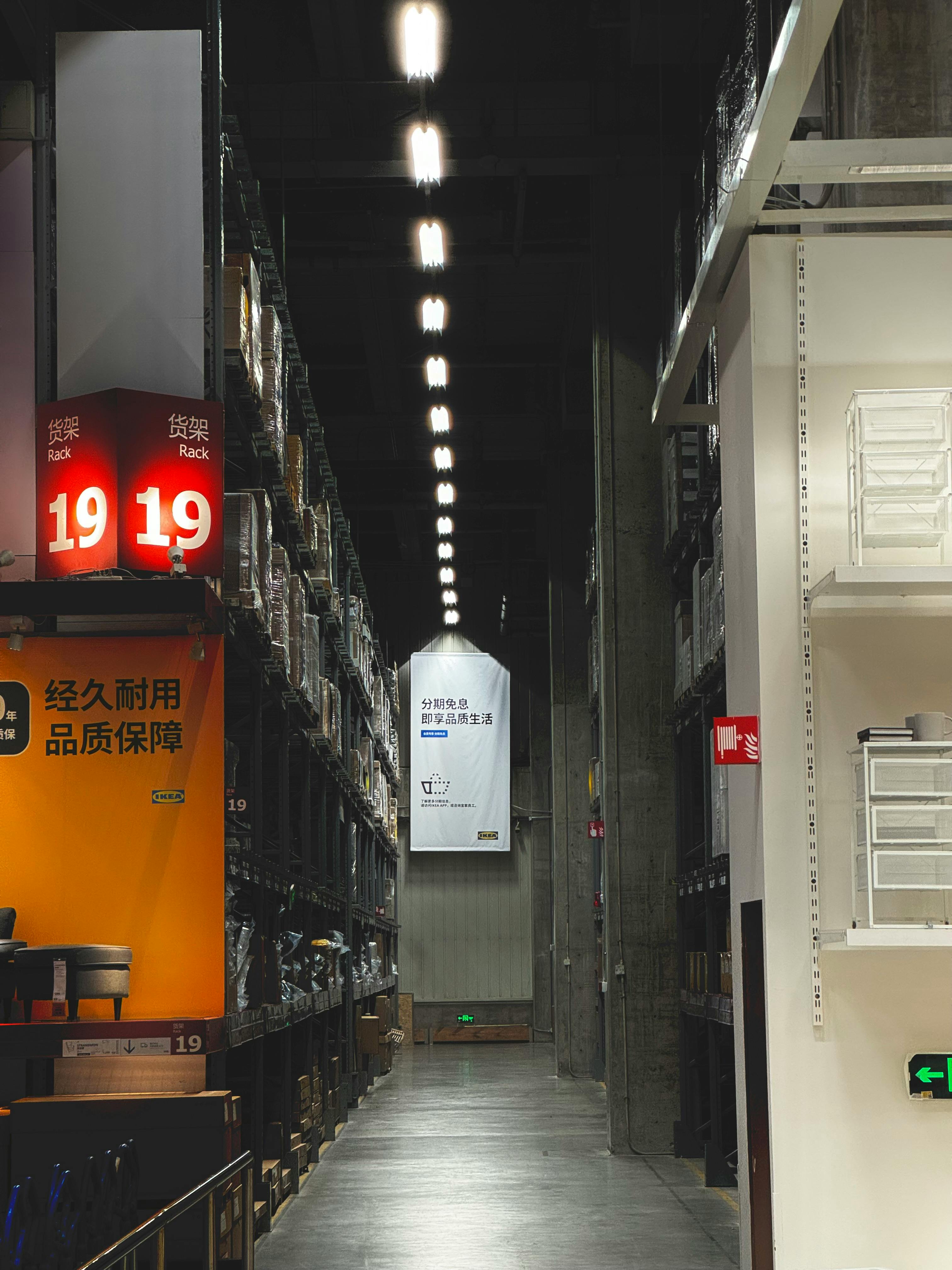 A well-lit warehouse aisle with organized shelves in a modern shopping center, Dong Li Qu, China.