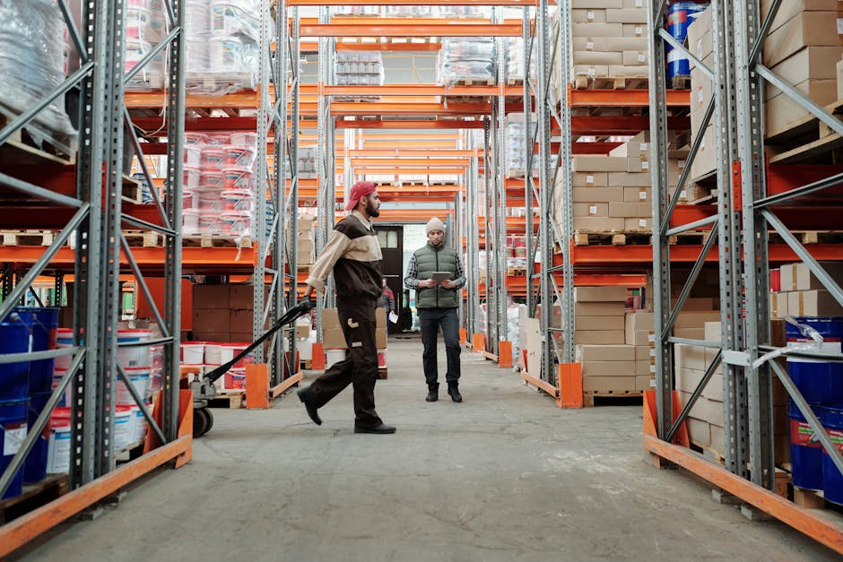 Two workers manage inventory in a spacious warehouse aisle.