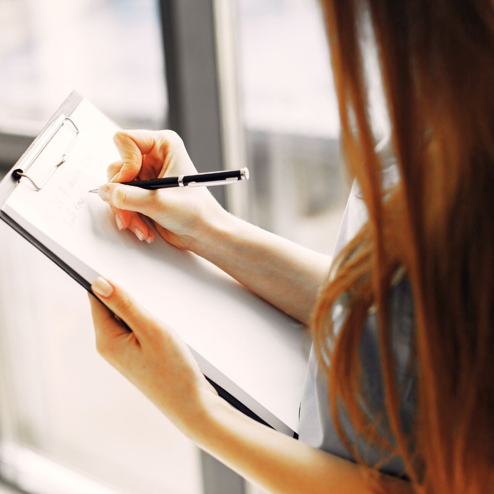 woman writing on clipboard